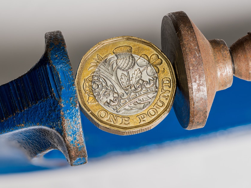 Pound coin being squeezed in a vice