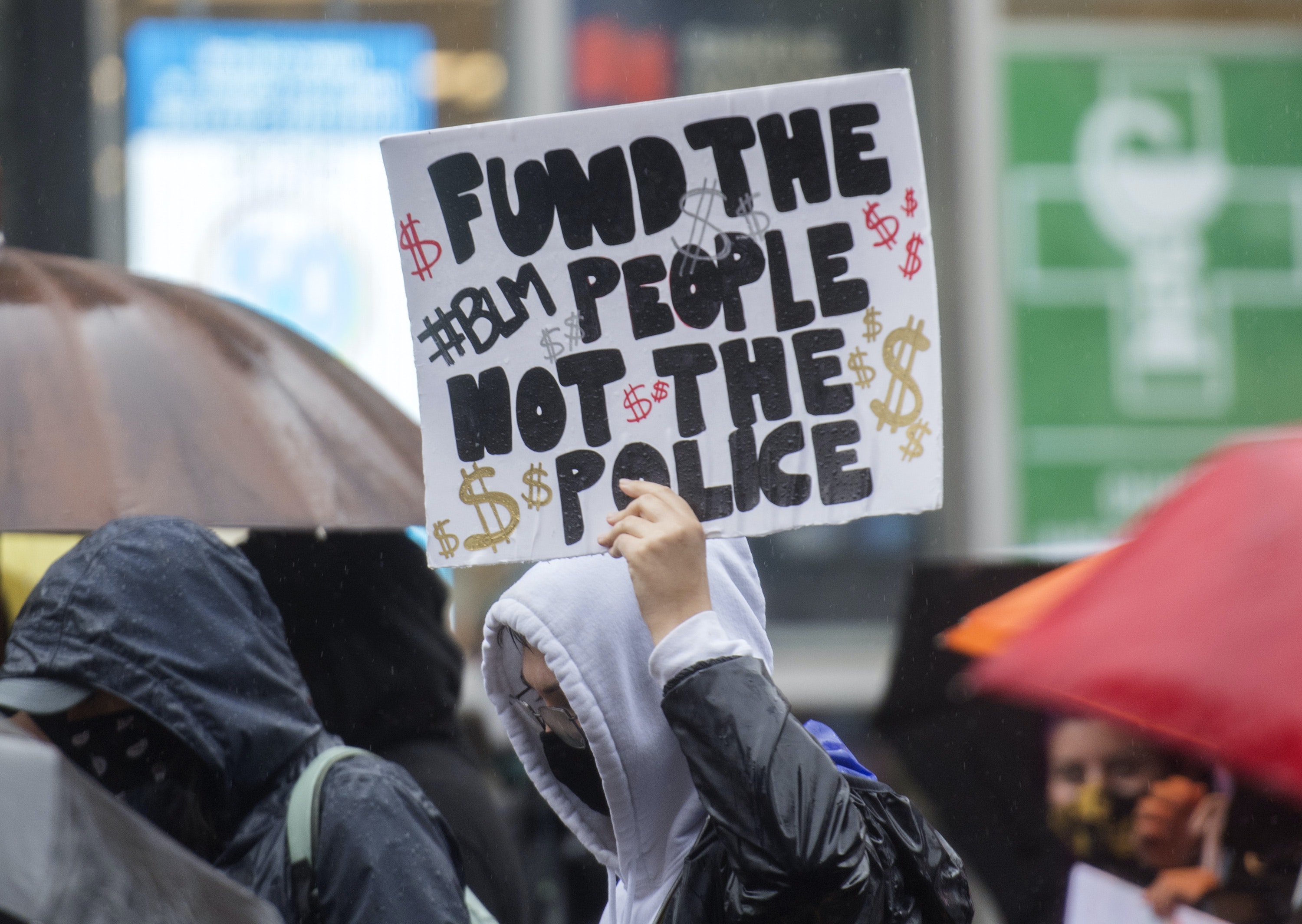 A sign at a demonstration reads, 'Fund the people not the police / BLM'